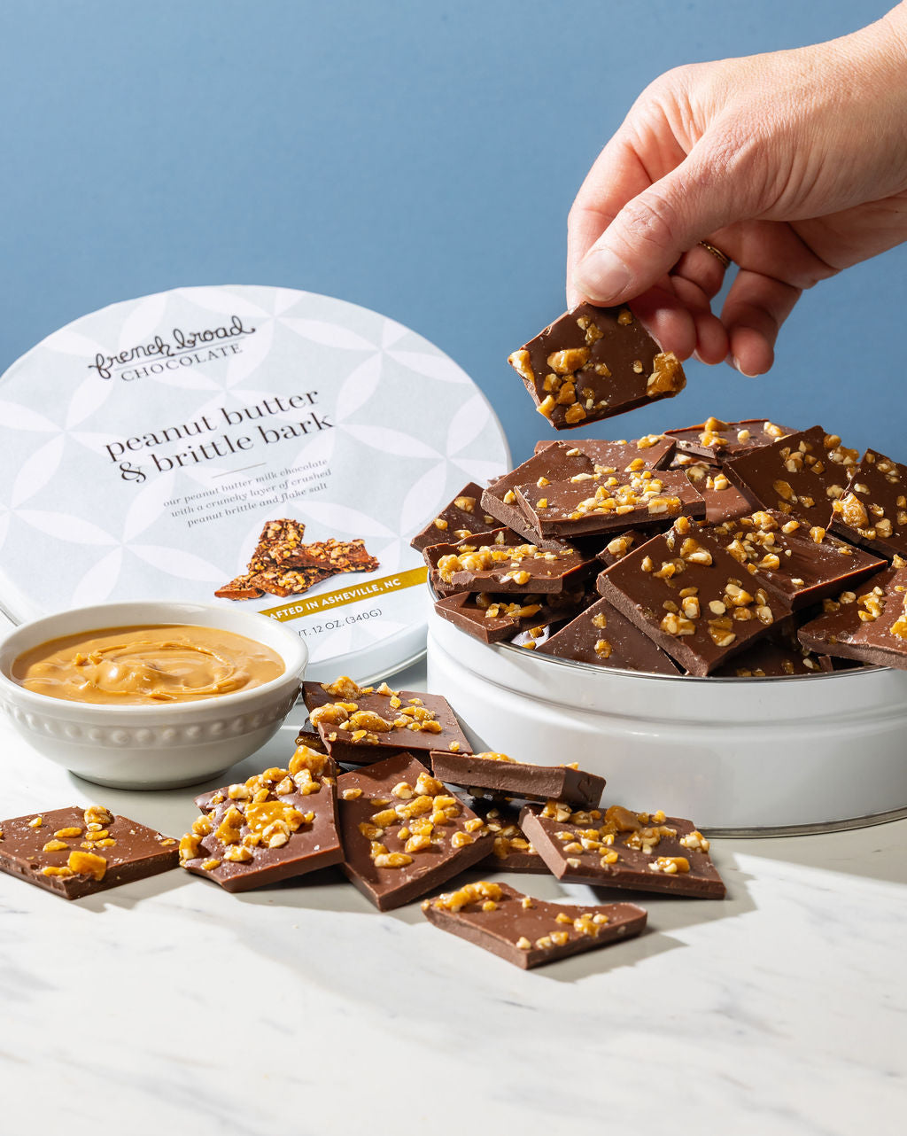 A tin of peanut butter and brittle bark broken into pieces