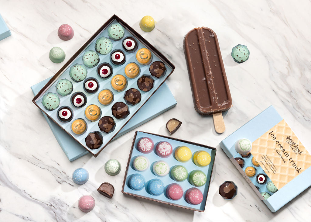 The Sunny Days gift set: a bright flatlay of pastel Ice Cream Truck bonbons, an assorted bonbon box, and a chocolate paleta on white marble