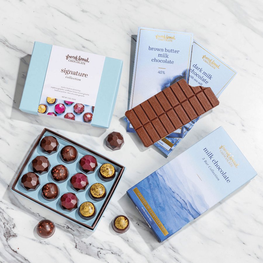 The Classic Signature gift set: an open box of jewel-toned bonbons with French Broad chocolate bars on marble
