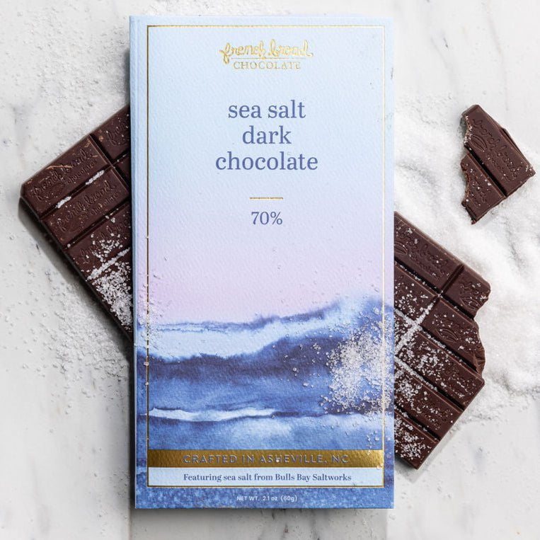 A Sea Salt Dark Chocolate 70% bar, broken with flaky sea salt, on marble