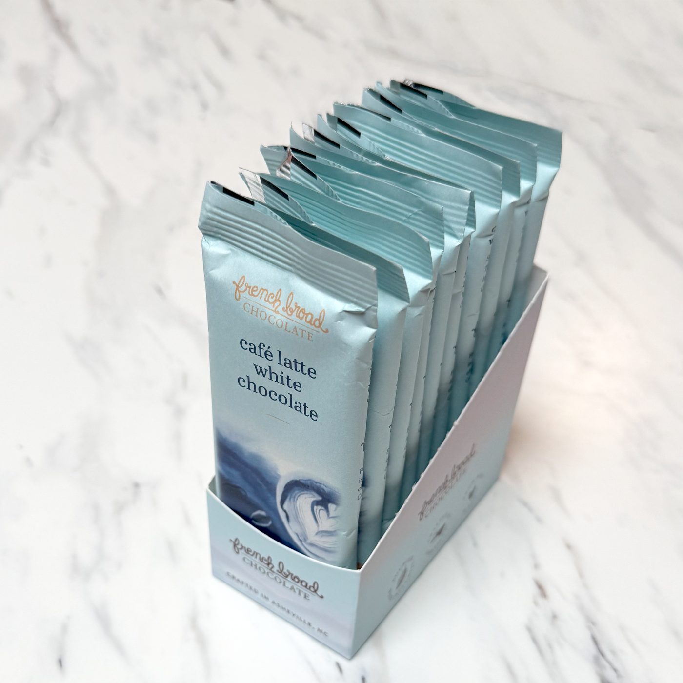 An open French Broad case pack with ten individually wrapped chocolate bars standing in the display box